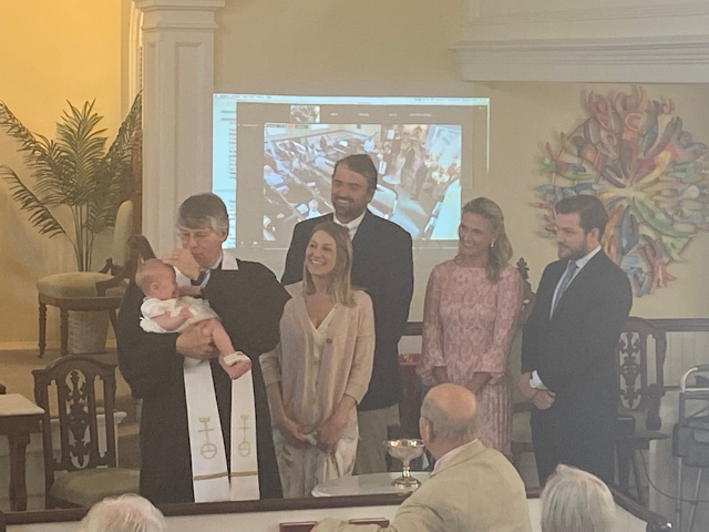 Child getting baptized surrounded by family